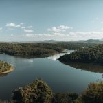 Rio cercado por vegetação densa de floresta, formando uma paisagem natural serena em Minas Gerais.