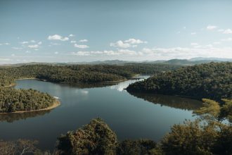 Rio cercado por vegetação densa de floresta, formando uma paisagem natural serena em Minas Gerais.