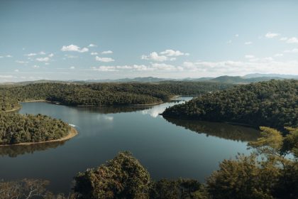 Rio cercado por vegetação densa de floresta, formando uma paisagem natural serena em Minas Gerais.