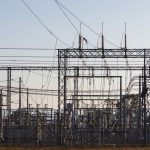 Subestação elétrica de alta tensão com estruturas metálicas e linhas de transmissão ao amanhecer