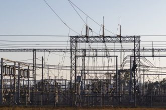 Subestação elétrica de alta tensão com estruturas metálicas e linhas de transmissão ao amanhecer