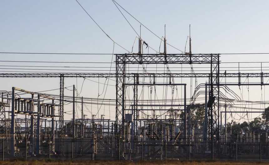 Subestação elétrica de alta tensão com estruturas metálicas e linhas de transmissão ao amanhecer