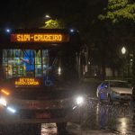 Ônibus urbano circula à noite sob chuva em Belo Horizonte.