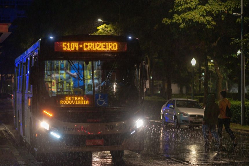 Ônibus urbano circula à noite sob chuva em Belo Horizonte.